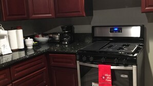 A kitchen with dark wooden cabinets, a stainless steel oven, and a black countertop. - Rigo’s Apartment  (South Gate)