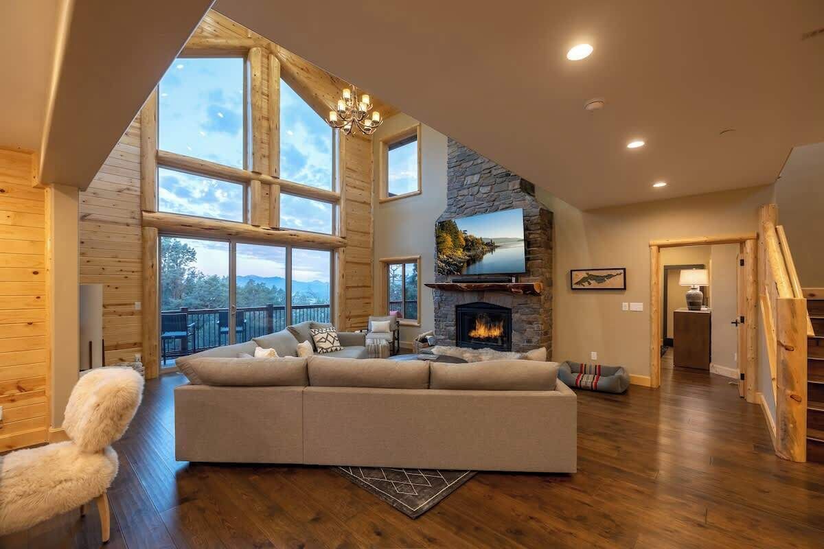 A spacious living room with a large sofa, a fireplace, and a view of the outdoors.