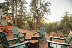 Una veranda con poltrone Adirondack e un’altalena, circondata da alberi.