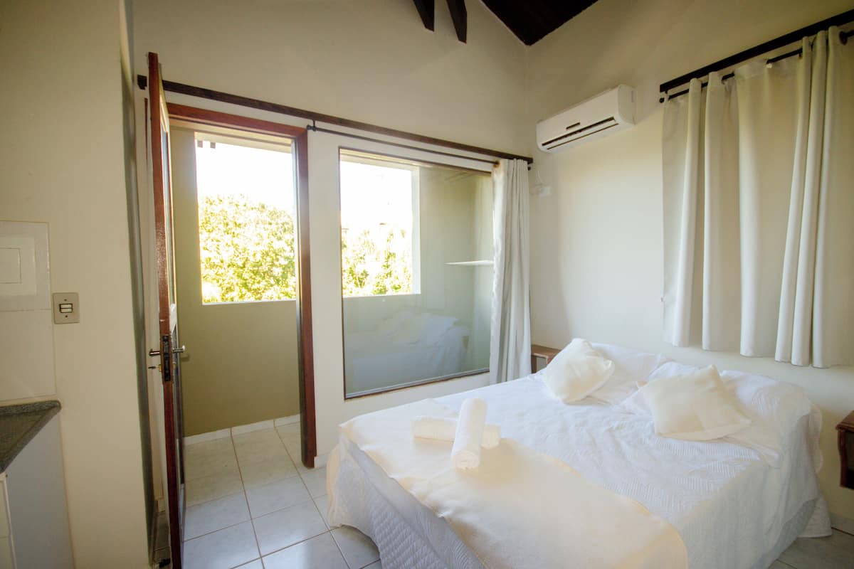 A bedroom with a bed, a sliding glass door, and an air conditioning unit.