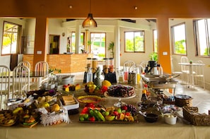 A breakfast buffet with various food items and a coffee station. - Pousada Elfos (Bombinhas)