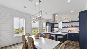 A modern kitchen with a large island, white cabinetry, and a view of the outdoors.
