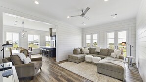 A spacious living room with a sectional sofa, a dining area, and a kitchen in the background.