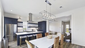 A modern kitchen with a central island, stainless steel appliances, and a hanging light fixture.