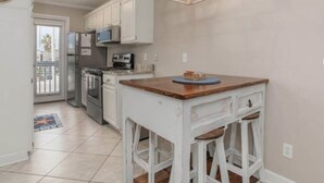 A kitchen with white cabinets, a wooden island with stools, a chandelier, and a clock on the wall.