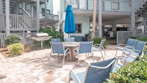 A patio with outdoor seating, a grill, and a blue umbrella.