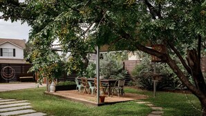 A covered patio with a table and chairs, surrounded by greenery and a stone pathway. - Elegant Historic Estate: Professionally Designed (Austin)