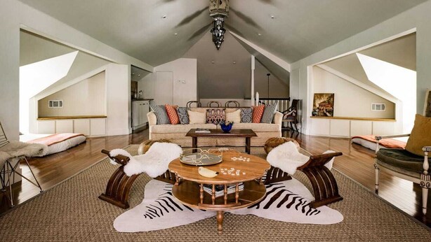 A spacious loft with a high ceiling, a central seating area with a round coffee table, and a view of the kitchen in the background. - Elegant Historic Estate: Professionally Designed (Austin)