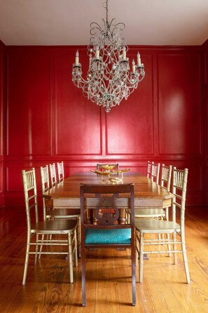 A dining room with a wooden table, eight chairs, and a chandelier.