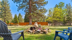 A backyard with a stone sculpture, two plastic chairs, and a wooden fence. - Mountain Breeze - Pet Friendly Read Our Reviews (Weed)