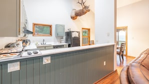 A kitchen with a built-in island, a mounted deer head, and a dining area with a brown leather couch. - Spacious hunting lodge hideaway with stunning views and Private River Access (Steelville)