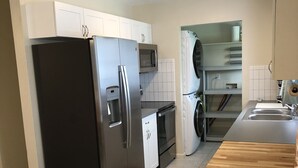 A modern kitchen with stainless steel appliances, a wooden countertop, and a bar stool.