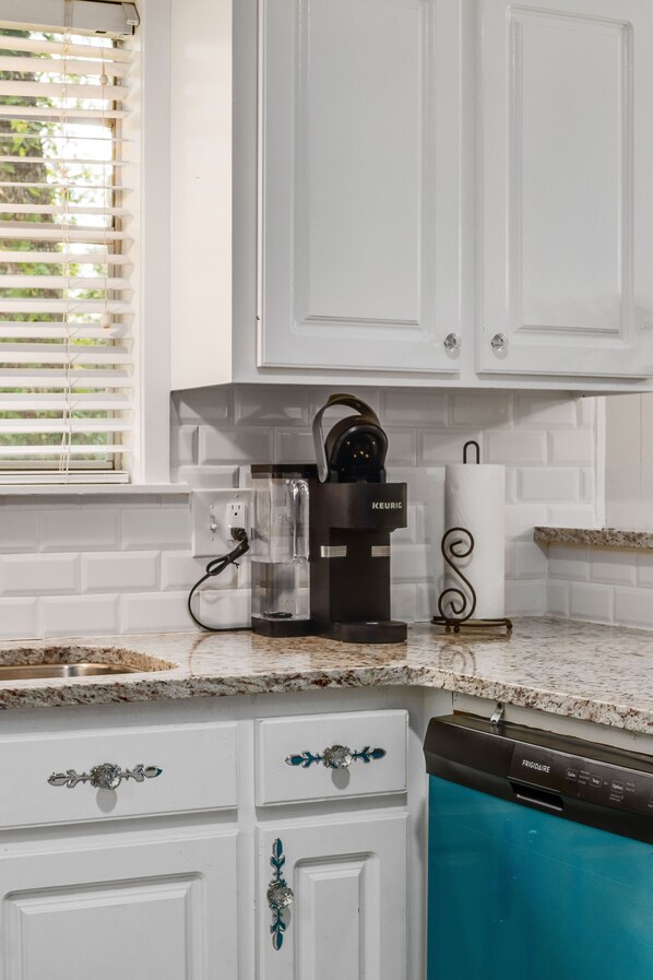 A kitchen with white cabinets, a coffee maker, a paper towel holder, and a dishwasher. - Cheerful, Relaxing Home Away From Home! (Jackson)