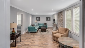 A spacious living room with a teal sofa, a beige armchair, and a coffee table. - Royal Chateau in the heart of Fondren! (Jackson)
