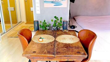 A wooden dining table with two chairs, a Finland poster, and potted plants.