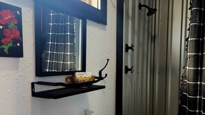 Baño con lavamanos blanco, grifo negro y cortina de ducha con estampado blanco y negro.