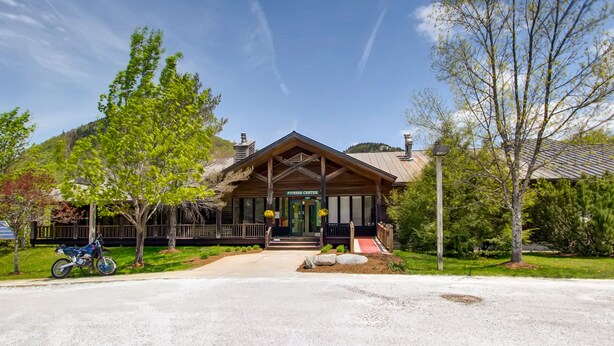 A lodge with a wooden exterior, a covered entrance, and a mountain backdrop. - PicoVillage Resort G301-Beautiful contemporary style 2-bedroom,2-bath condo with the comfort of home (Killington)