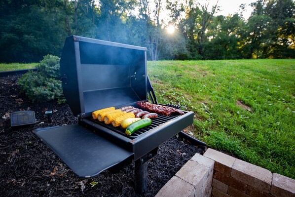 Una parrilla portátil con diversos tipos de carne y verduras asándose al aire libre.