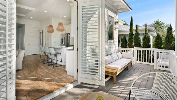 An open sliding door leading to a dining area with a kitchen in the background. - Resort Pool · 4BR/3BA · 30A · Golf Cart + 8 Bikes (Santa Rosa Beach)