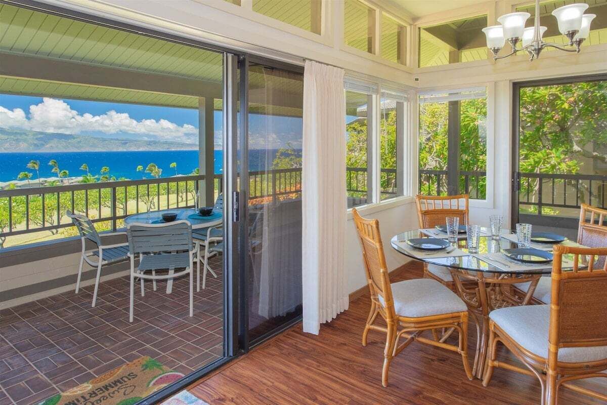 Un espace repas avec vue sur l’océan, une porte vitrée et des meubles en bois.