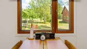 A room with a wooden table, a radio, and a view of a garden and a house through a window. - Lamminranta by Interhome (Lemi)