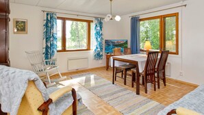 A cozy room with a wooden table and chairs, a radiator, a window with curtains, and a painting on the wall. - Lamminranta by Interhome (Lemi)