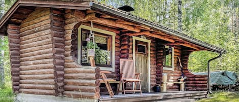 A log cabin with a porch, a chair, and a table.