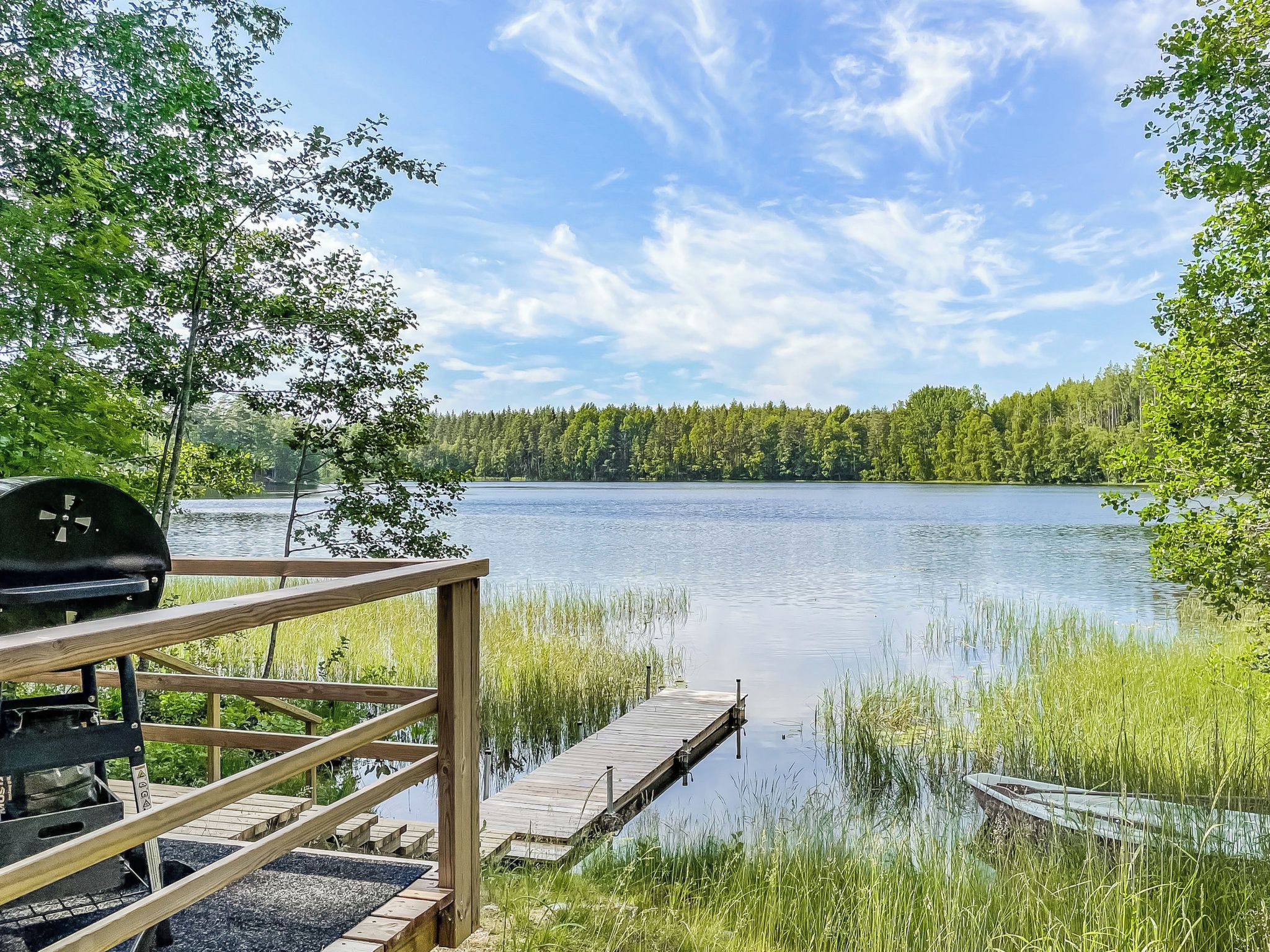 A wooden dock extending into a calm lake surrounded by dense forest.