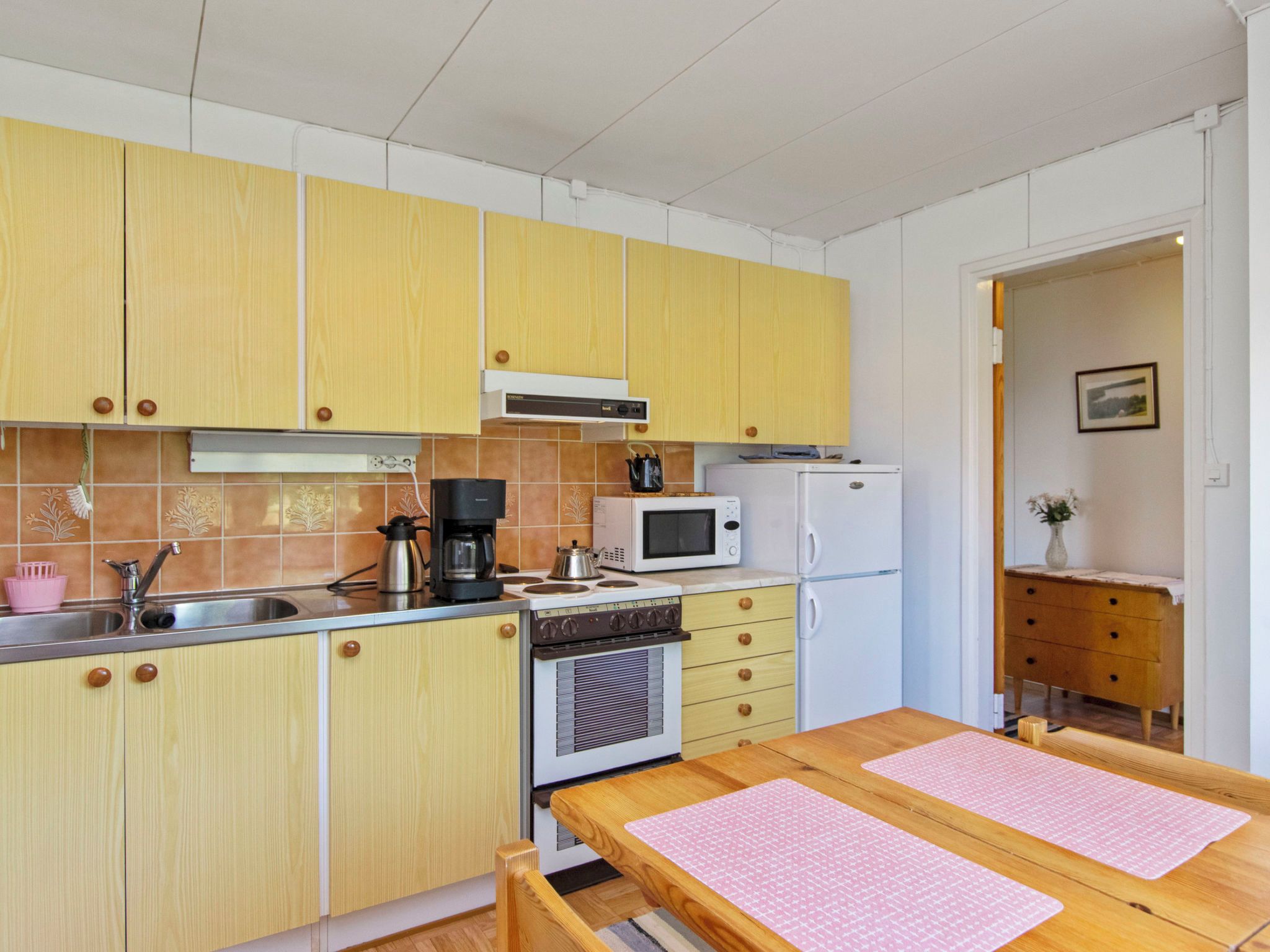 Una cucina compatta con mobili in legno, un forno a microonde, una macchina da caffè e un fornello.