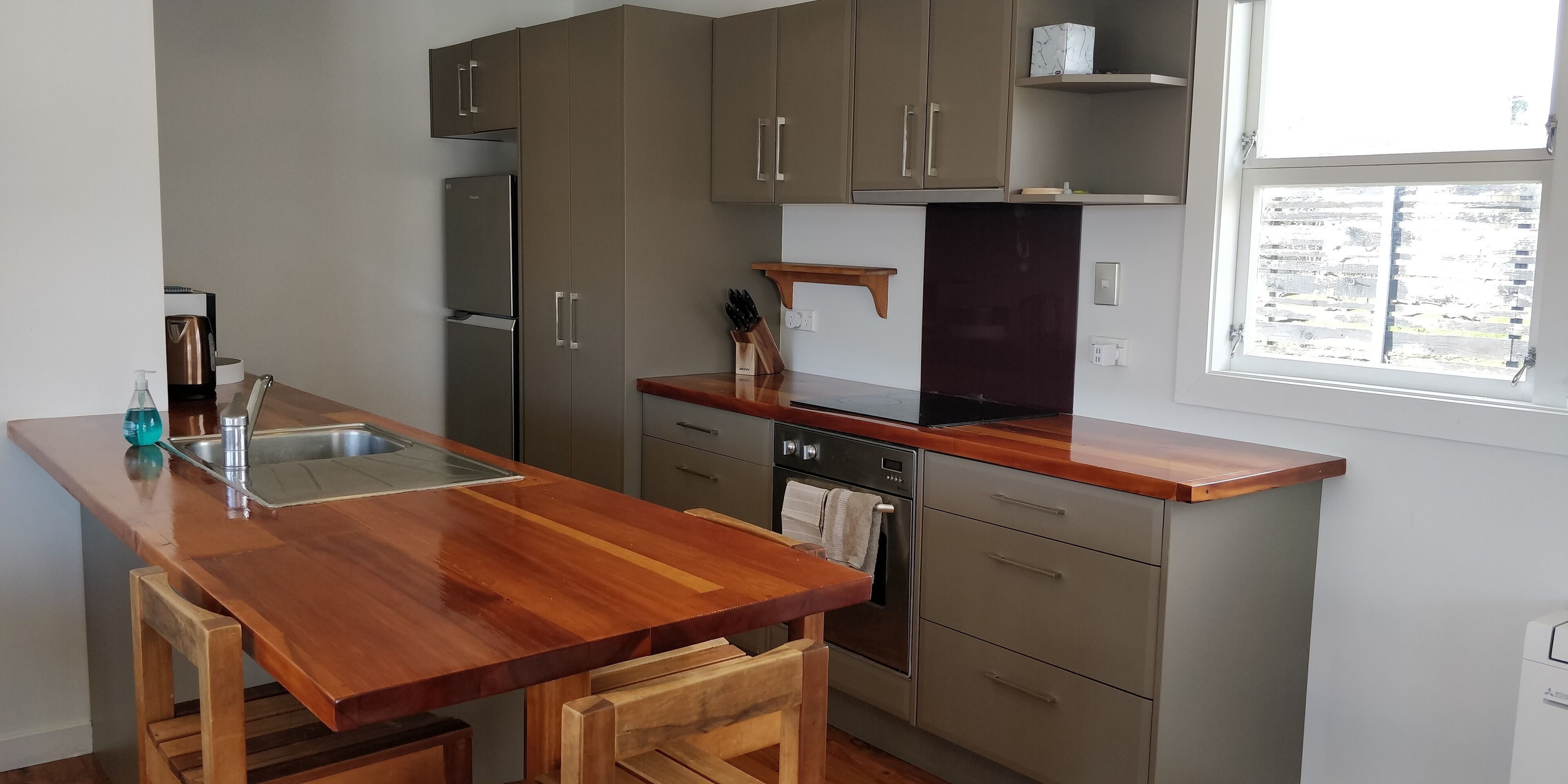 A modern kitchen with wooden countertops, stainless steel appliances, and a window providing natural light.