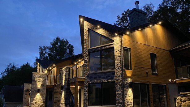 A modern two-story house with stone and wood exterior, large windows, and a well-lit driveway. - NEW! La Marie-Pierre Ski/Golf Mont Tremblant (Mont-Tremblant)