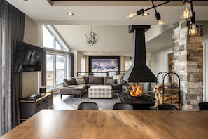 A modern living room with a fireplace, a large sofa, and a dining table.