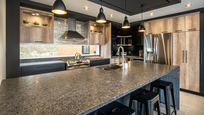 A modern kitchen with a granite countertop, stainless steel appliances, and wooden cabinets. - NEW! La Marie-Pierre Ski/Golf Mont Tremblant (Mont-Tremblant)