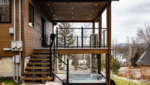 A wooden cabin with a hot tub on a deck, surrounded by a snowy landscape. - NEW! La Marie-Pierre Ski/Golf Mont Tremblant (Mont-Tremblant)