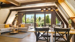 A spacious loft-style room with a dining area, large windows, and a view of the outdoors. - Holiday Home 'Auszeit' with terrace & garden (Tennenbronn)