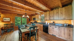 L’intérieur d’un chalet en bois comprend un coin repas, une cuisine et de grandes fenêtres.