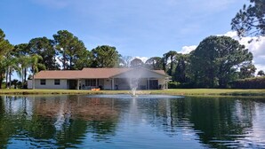 Une maison avec une fontaine dans un bassin, entourée d’arbres.