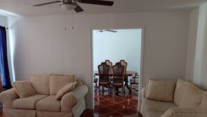 Un salon avec deux canapés beiges, une table à manger avec des chaises et un ventilateur de plafond.
