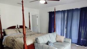 Une chambre à coucher avec un lit à baldaquin, un canapé et un ventilateur de plafond.