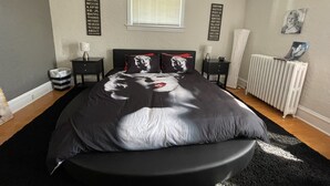 Ein Schlafzimmer mit einem Bett, einem Deckenventilator, einem Fenster und zwei Wandbildern mit motivierenden Sprüchen.