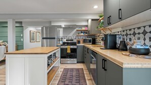 A modern kitchen with stainless steel appliances, wooden countertops, and a patterned backsplash.