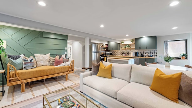 A modern living room with a sofa, coffee table, and a kitchen in the background.