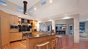 Une cuisine moderne dotée d’un îlot central, de planchers en bois et d’appareils électroménagers intégrés.