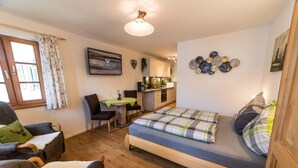 Une petite chambre comprenant un lit, un bureau et une kitchenette.