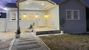 Ein modernes Haus mit überdachter Veranda, einem kleinen Garten und einem umzäunten Hinterhof.