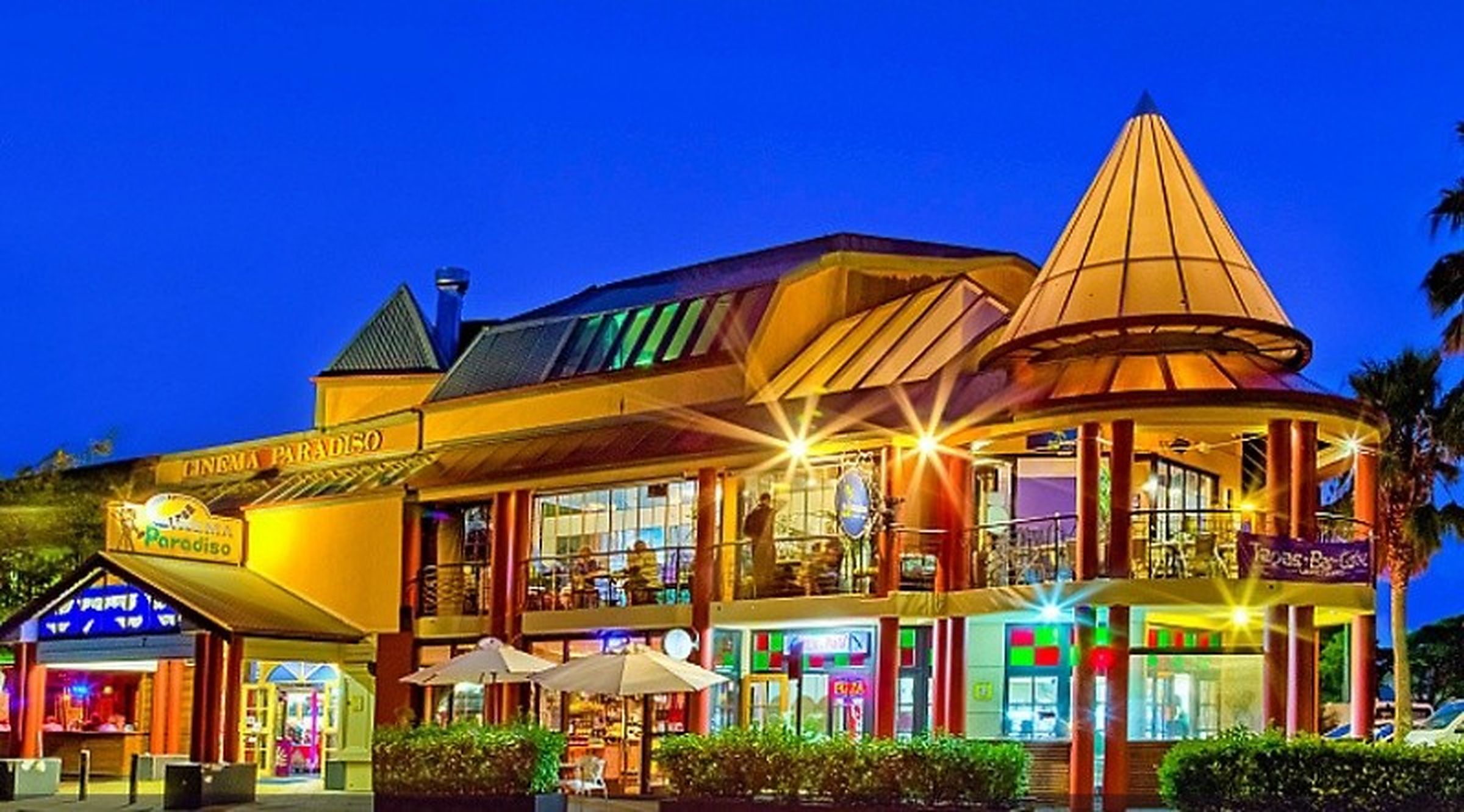 A multi-story building with a prominent conical roof, a cinema, and various shops on the ground floor.