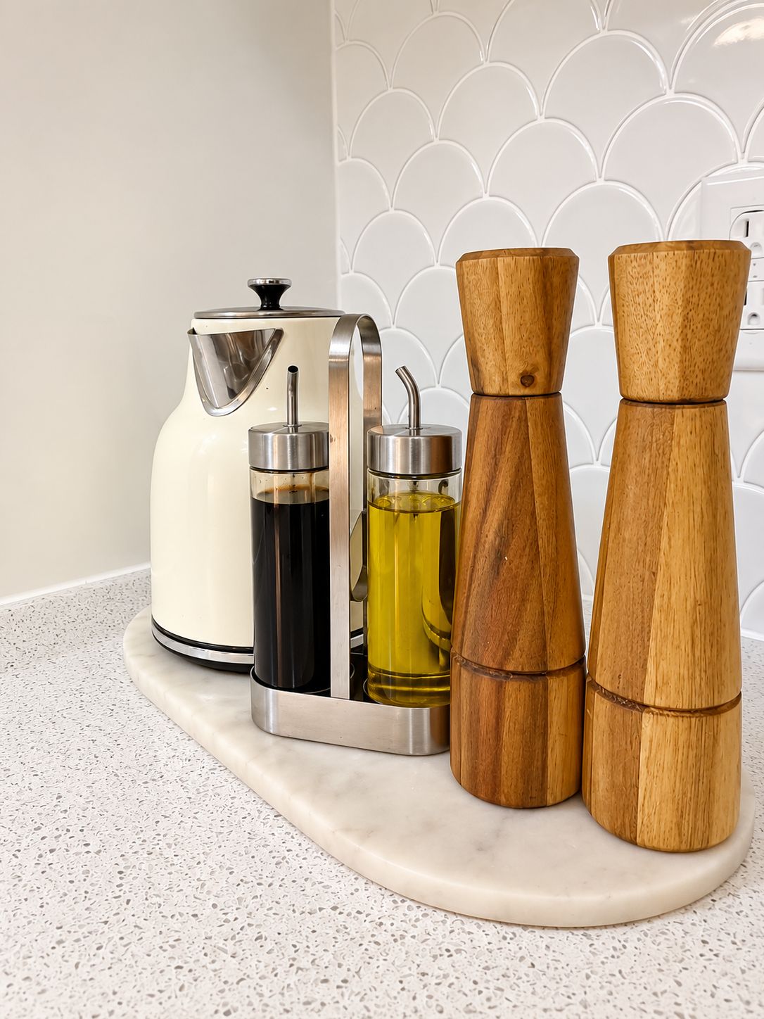 A kitchen counter with a white kettle, two metal containers, and two wooden salt and pepper shakers.