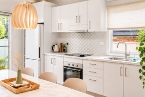 A modern kitchen with white cabinets, a black stove, and a window with a view of greenery.