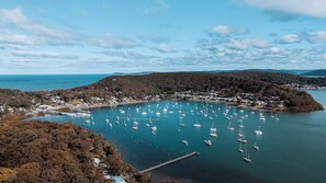 A coastal town with a marina filled with sailboats, surrounded by hills and a clear sky.