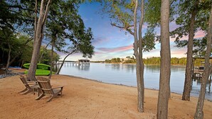 A beach with wooden chairs, a kayak, and a dock extending into calm water. - Hanesbee Escape w/Beach, Hot Tub & Optional Boat Rental (Mooresville)